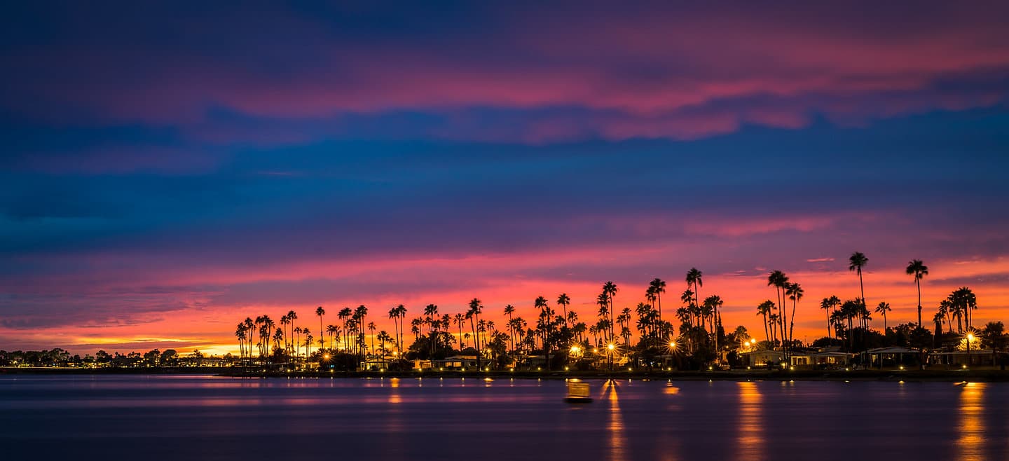 Palm silhouettes and a vivid sunset over the waters of Mission Bay