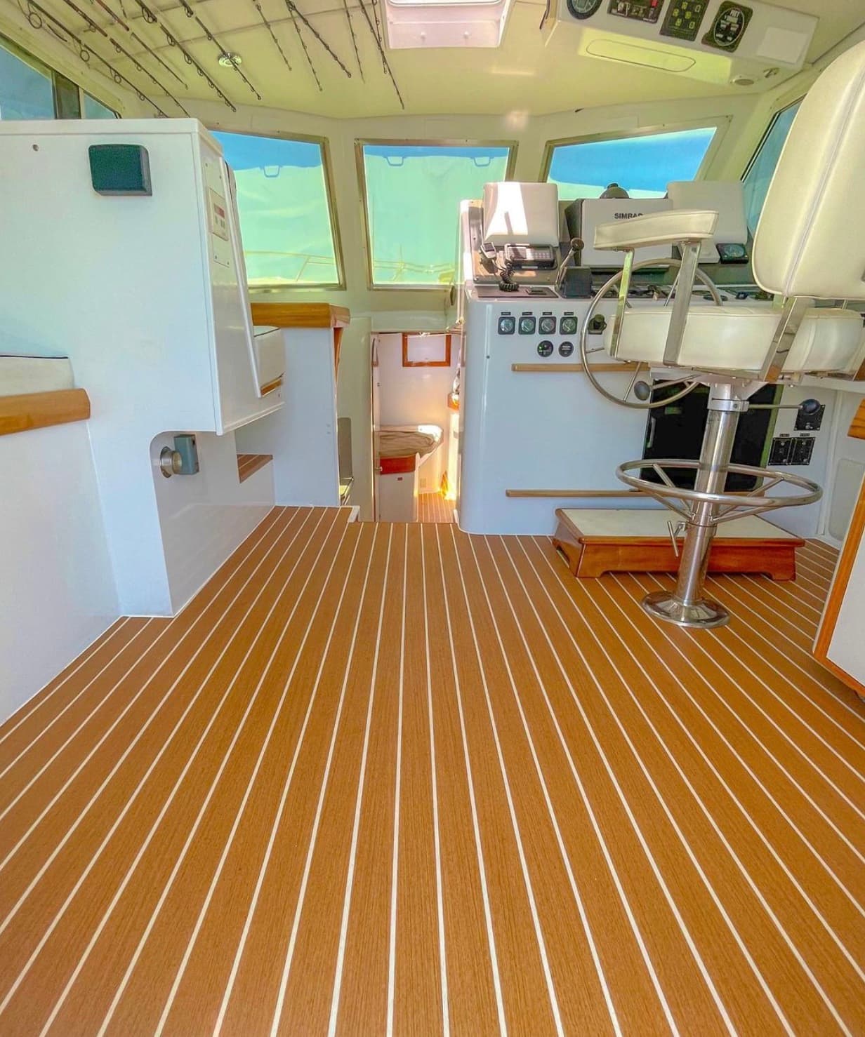 Bluebill's cabin helm: teak-style striped sole, helm chair and Simrad screens