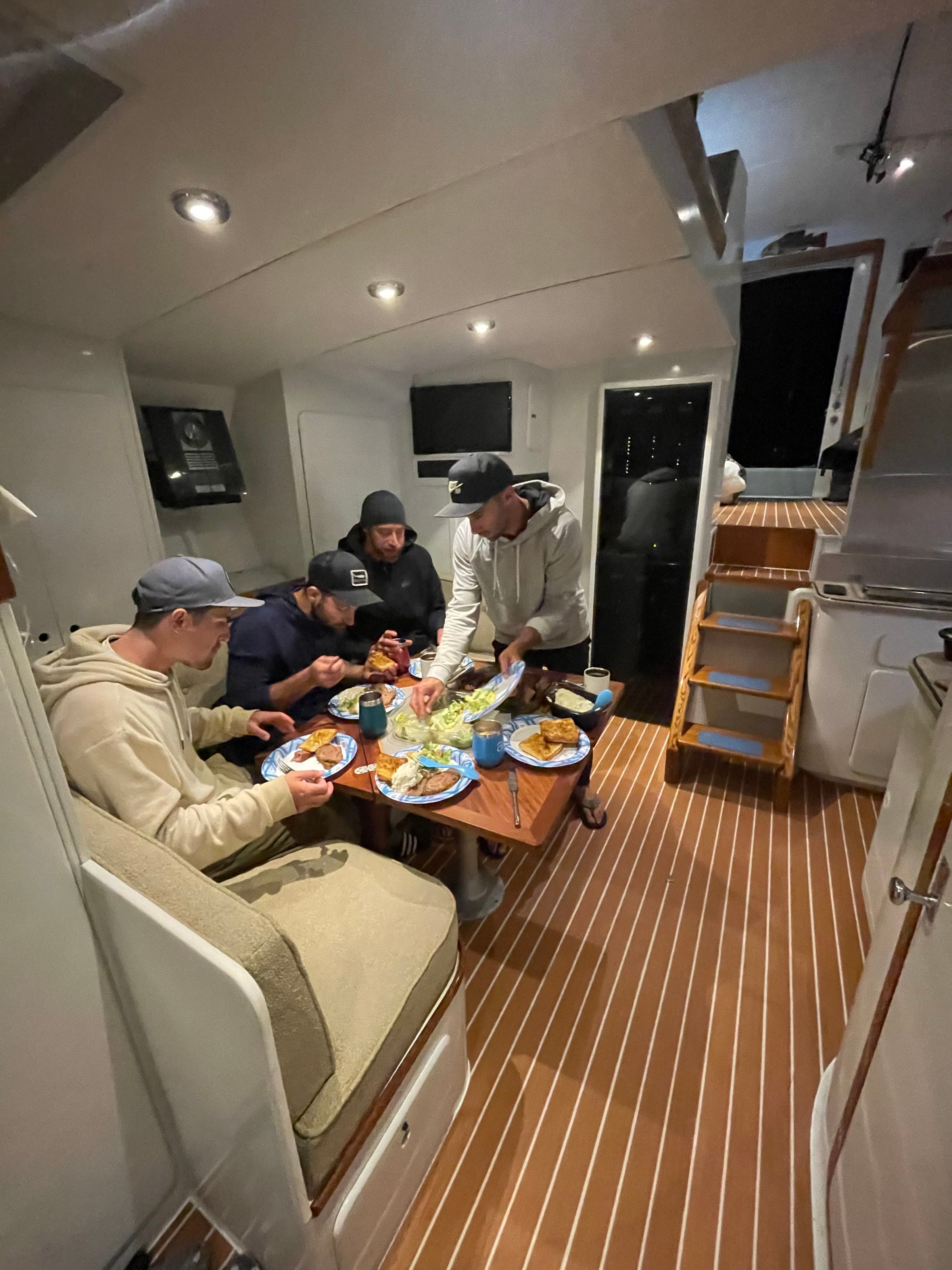 Guests eating dinner around the dinette in Bluebill's salon at night