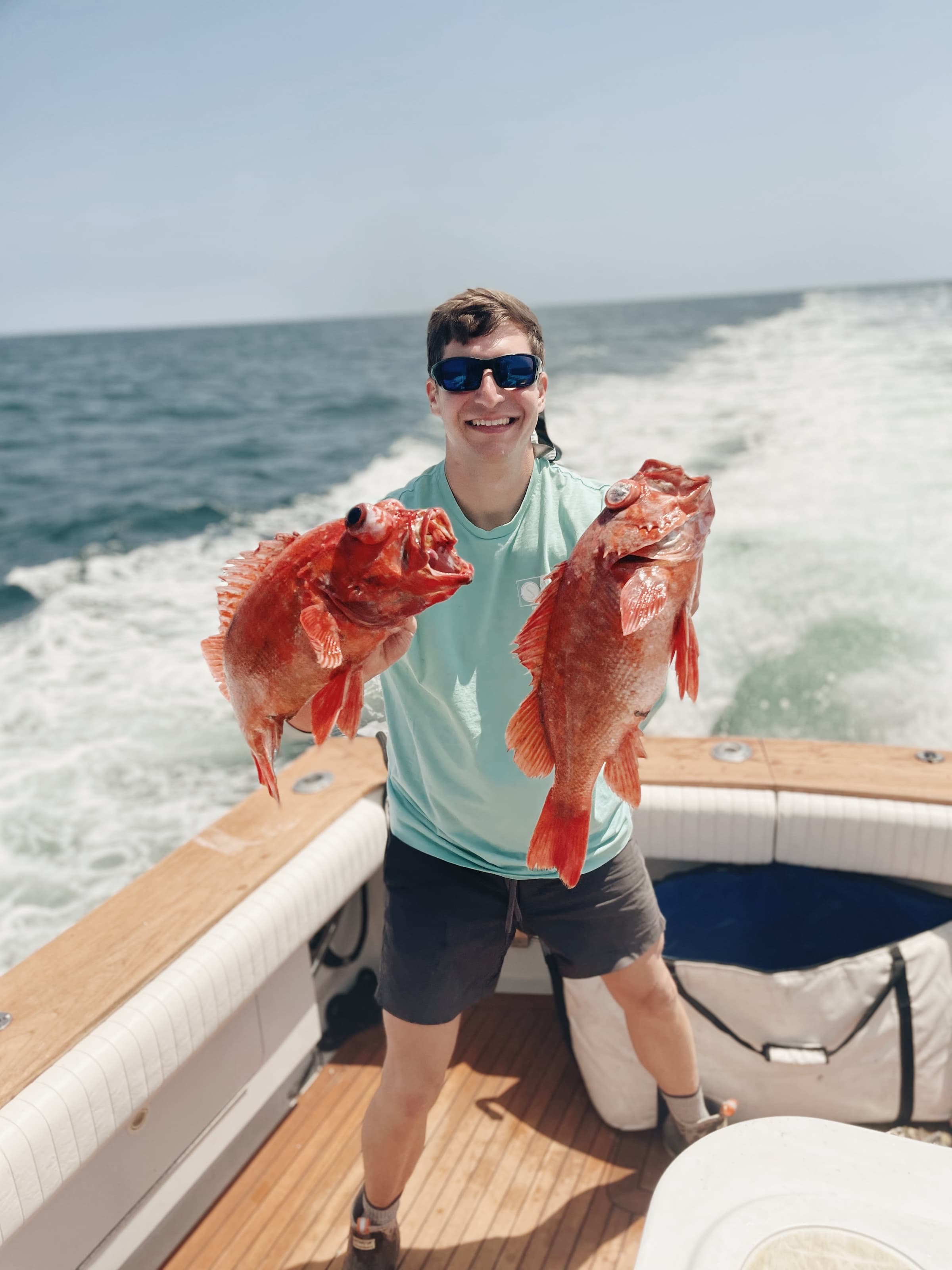 An angler aboard holding up a fresh-caught rockfish